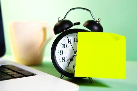 Alarm clock with sticky note and cup of coffee on green background Stock Photos
