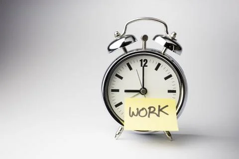 Alarm clock with sticky paper note on white background.. Stock Photos