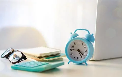 Alarm clock on a table with laptop computer and books Foto stock