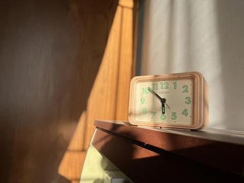 Alarm clock on a table under the sunlight Stock Photos