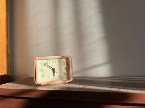 Alarm clock on a table under the sunlight Stock Photos