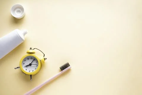 Alarm clock, toothbrush and toothpaste on a yellow background with space for  Stock Photos