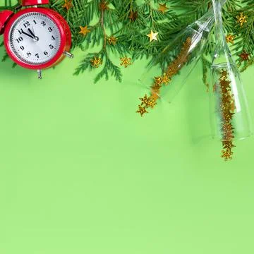 Alarm clock  with tree branches and glasses of champagne on green paper backg Stock Photos