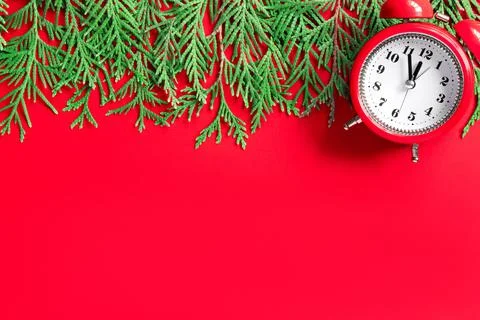 Alarm clock  with tree branches on red paper background. 5 minutes before the Stock Photos