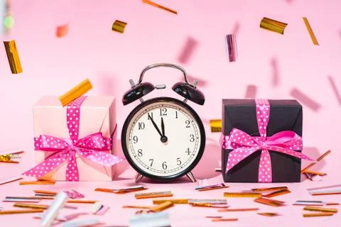 The alarm clock, which shows almost midnight among the multicolored confetti and Foto stock