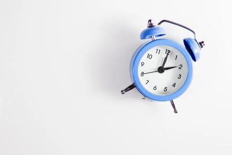 Alarm clock on a white background with shadows. Two o'clock in the afternoon Stock Photos