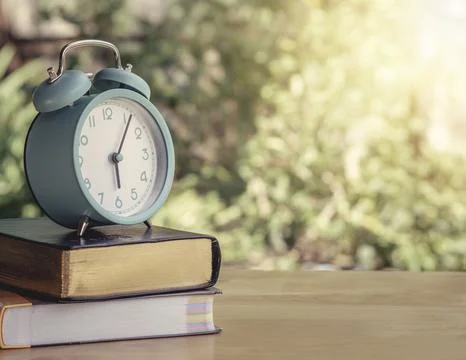 Alarm clock on workbook and textbook on the table or work desk with hot cof.. Stock Photos