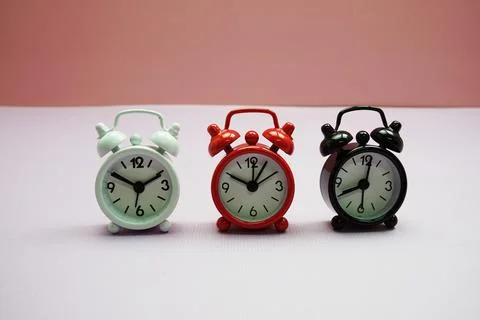 Alarm clocks with different time composition on pink  background Foto stock