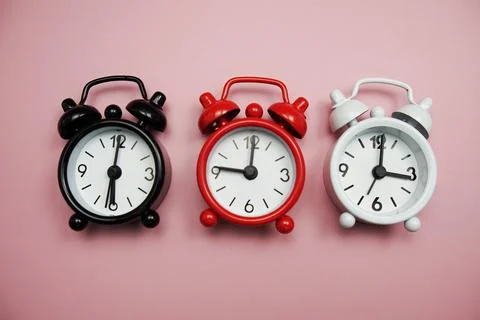 Alarm clocks with different time Flat lay composition on pink  background; Stock Photos