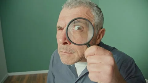 Alarmed Man Looking Suspiciously Through a Magnifying Glass. Stock Footage 166650245