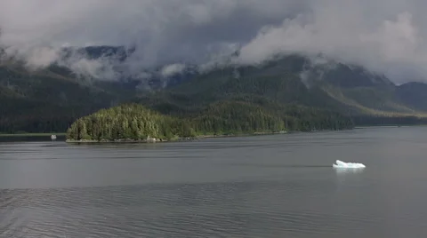Alaskan Coast with Forest, Mists, Mountains, and Passing Iceberg Stock Footage 50742329