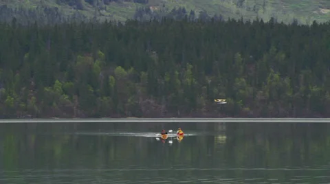 Alaskan Floatplane Taking Off Beyond Kayakers on a Calm Lake Stock Footage 36623429