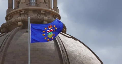 The Alberta flag proudly waves against the backdrop of the Legislature Building Stock Footage 310083572
