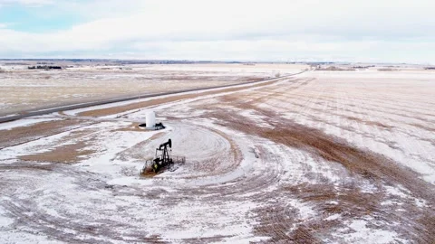 Alberta oil pumpjack working in the winter season near the Canadian Rockies Stock Footage 233616448