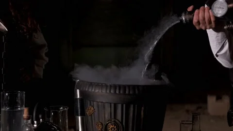 An alchemist man pours liquid nitrogen from a duvar vessel into a pot Stock-Footage 168261406