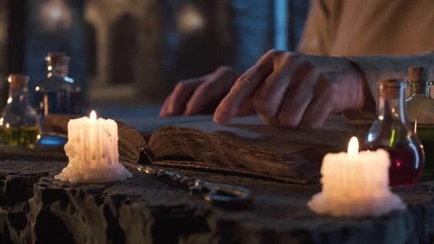 Alchemist reading an ancient book by candlelight. Stock Footage 313115407