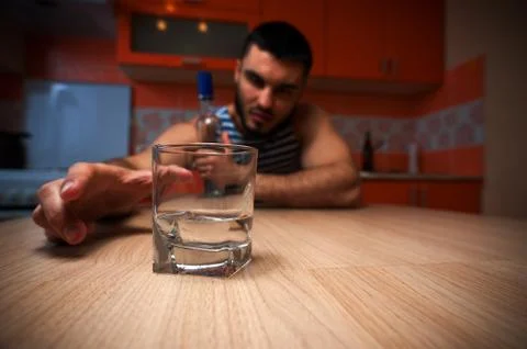 Alcohol addicted man sitting in kitchen at home Stock Photos