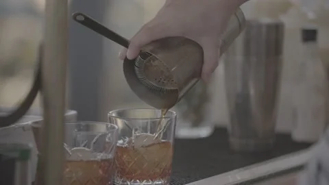 Alcohol being poured into two whiskey glasses in bar Stock Footage 201159249