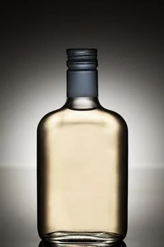 Alcohol bottle on grey gradient background, side view. Stock Photos