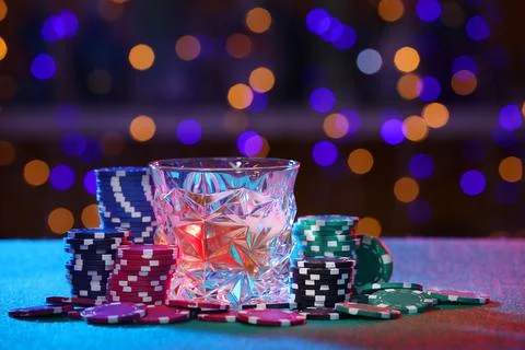 Alcohol drink and casino chips on table against blurred lights Stock Photos