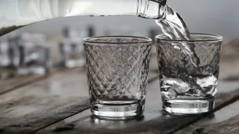 Alcohol flow in a glass with ice. Vodka pouring Stock Footage 102484774