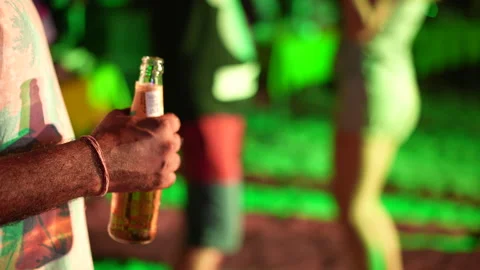 Alcoholic drinking beer bottle at night club. Drunk man hold alcohol beverage. Stock Footage 240073672
