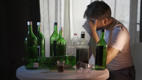 Alcoholic drinking behind bottles of alcohol, alcoholism Stock Footage 156191276