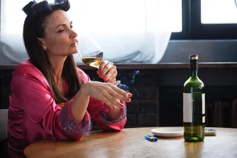 Alcoholism problem concept. Sad middle aged woman in stress sits in the kitchen Stock-Fotos