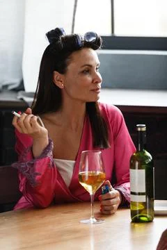 Alcoholism problem concept. Sad middle aged woman in stress sits in the kitchen Stock Photos
