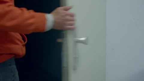 Alert security officer slowly opens door and slips into gloom Stock Footage 322923637