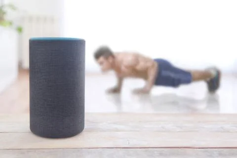 Alexa echo plus device running a fitness skill. Man doing pushup workout at home Stockfoto's