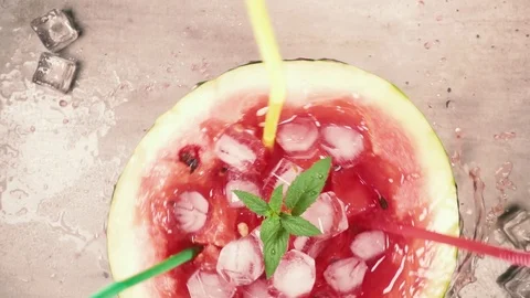 Alf of watermelon with ice, mint and slices of watermelon and a straw revolves Stock Footage 93554629