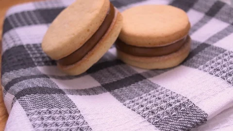 Alfajor and Dulce de Leche on Gray Kitchen Rag Pan Over Wood Video stock 129351277