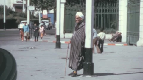 Algiers - 1975: Elderly man with a cane looks up at the sky on a sunny city day 스톡 동영상 240113593