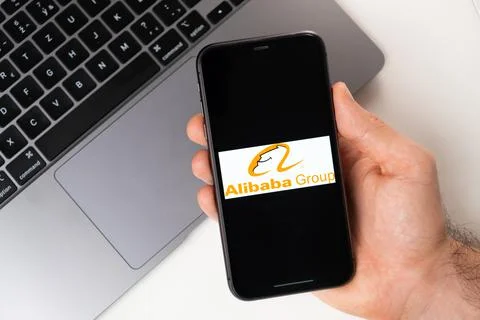 Alibaba Group the application is open in the smartphone. The man is holding a Stock Photos