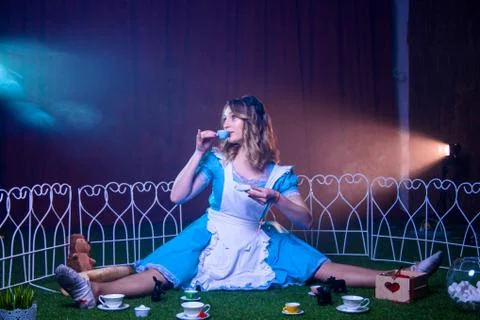Alice is drinking tea from a small cup in a circle of magical animals Foto stock