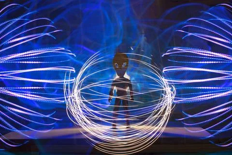 Alien figure surrounded by light trails and energy patterns Foto stock