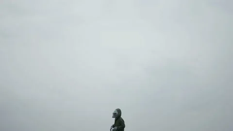 Alien in green suit stands alone in sky,alien arrived on earth rubbing his hands Stock Footage 145111086