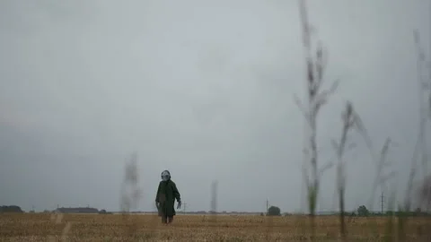 An alien in a green suit stands alone in field, looks around, waves his hand, Stock Footage 145111131