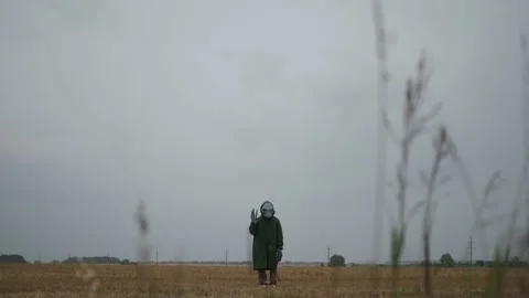 An alien in a green suit stands alone in field, looks around, waves his hand, Stock Footage 145111142