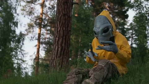 Alien in yellow suit in forest talking on the phone, UFO concept, space, Stock Footage 142121985