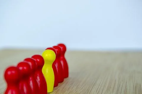 Aligned red figures with one yellow peg stood out to speak up. Stock Photos