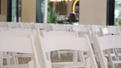 Aligned White Chairs in Bright Indoor Setting with Greenery Stock Footage 336745845