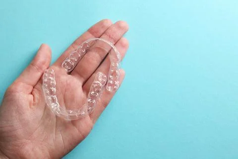 Aligners for aligning teeth on a blue background in a female hand Stock Photos