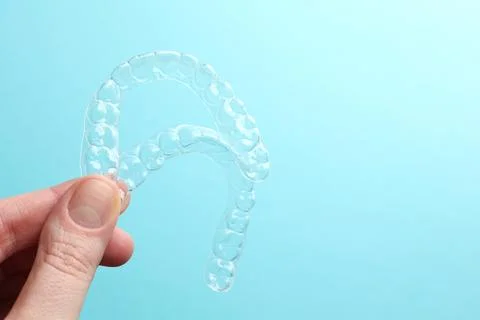 Aligners for aligning teeth on a blue background in a female hand Stock Photos