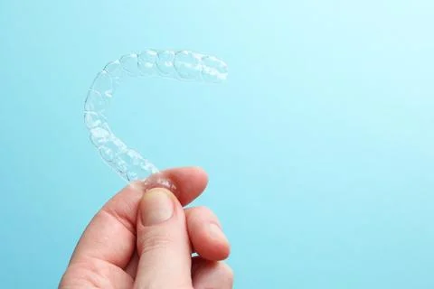 Aligners for aligning teeth on a blue background in a female hand Stock Photos