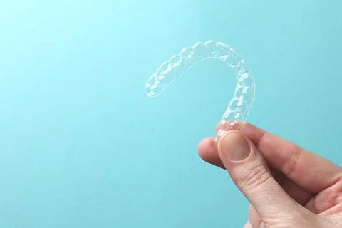 Aligners for aligning teeth on a blue background in a female hand Stock Photos