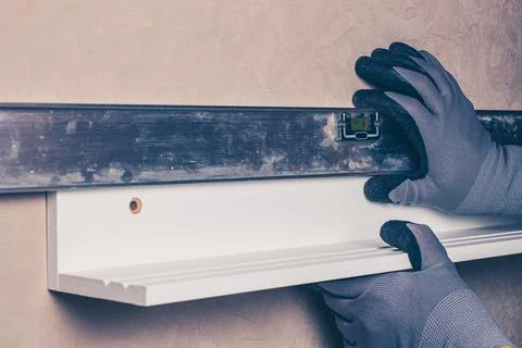 Alignment of the hanging shelf with the level of the gloved worker Stock Photos