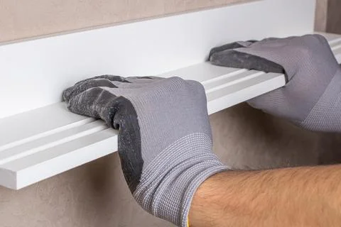 Alignment of the hanging shelf with the level of the gloved worker Stock Photos