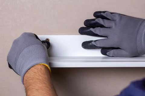 Alignment of the hanging shelf with the level of the gloved worker Stock Photos